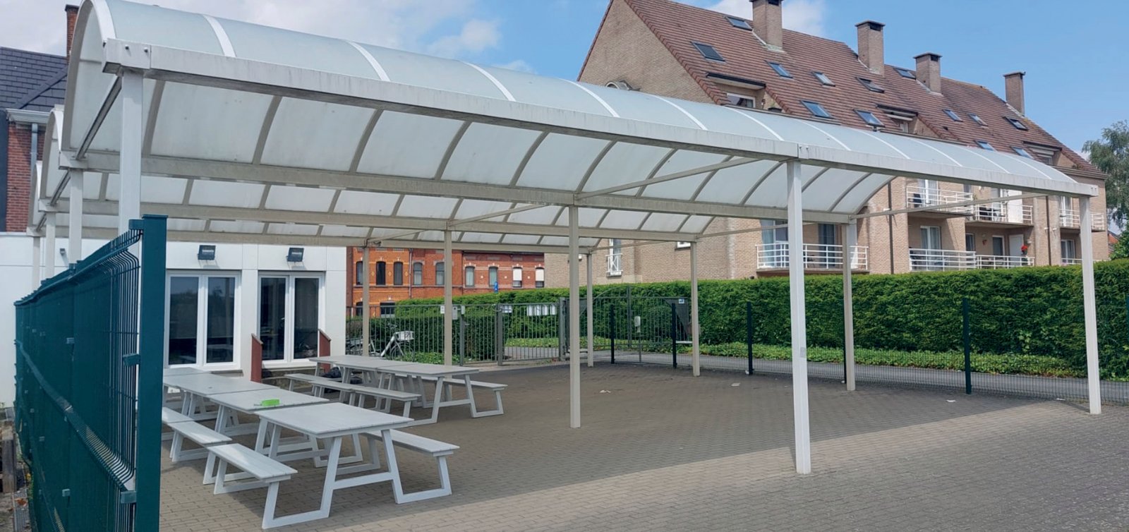 Schooloverkapping met gebogen polycarbonaatdak en witte structuur – Coverit