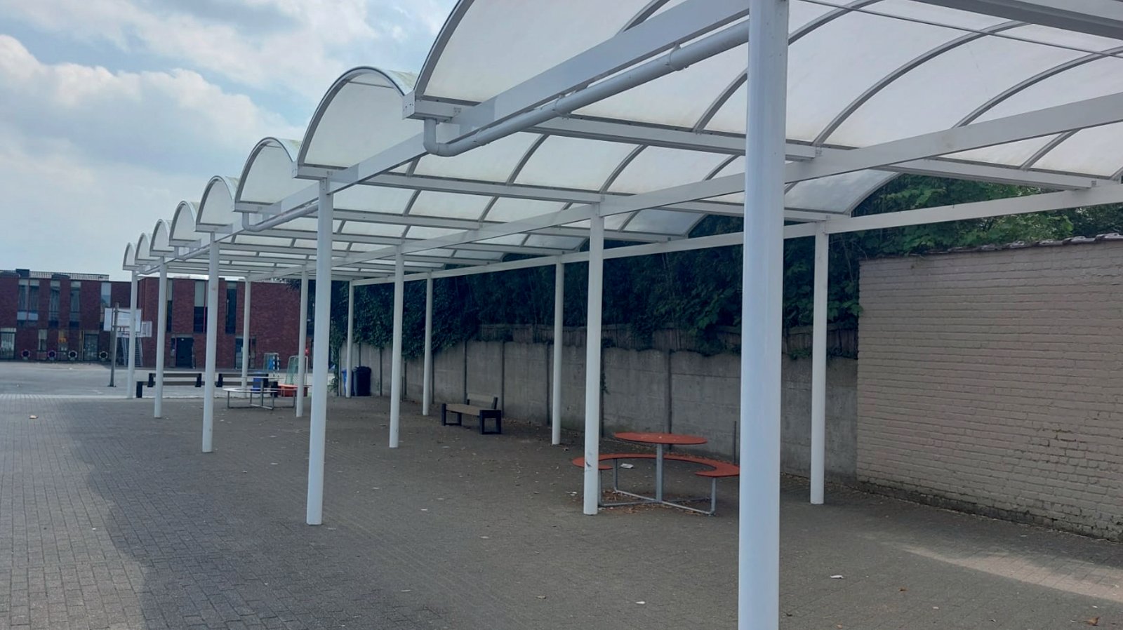 Overkapping met gebogen polycarbonaatdak op een schoolspeelplaats – Coverit