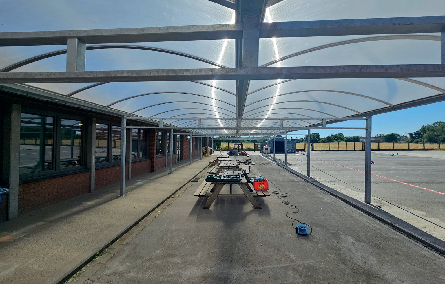 Binnenaanzicht van een schooloverkapping met gebogen polycarbonaatdak – Coverit